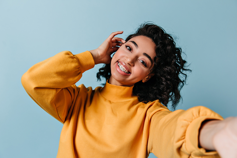 Vibrant young woman with braces tucking her beautiful curly hair behind her ear