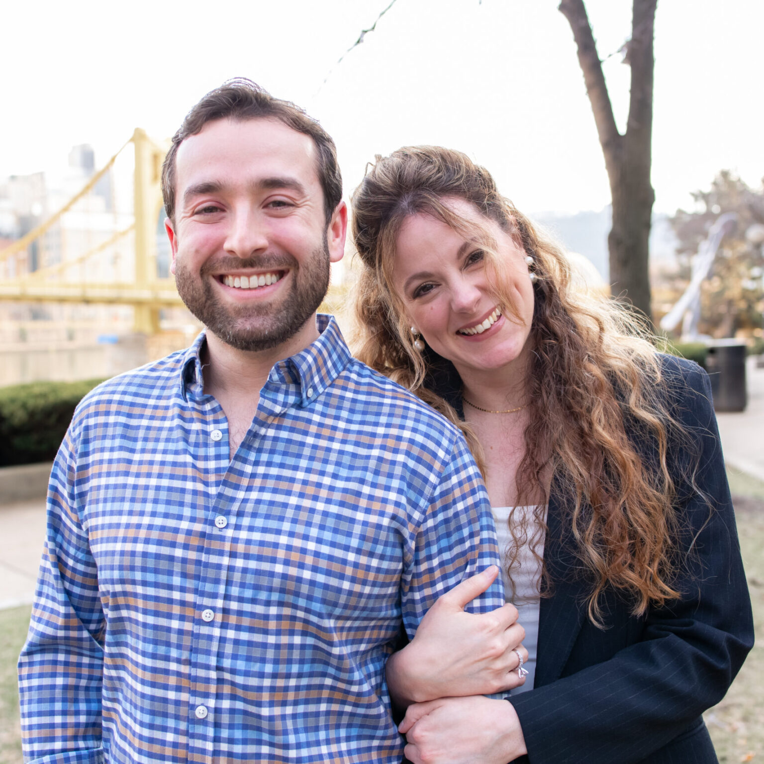 Dr. Crell and his wife smiling and posing in front of the Pittsburgh skyline