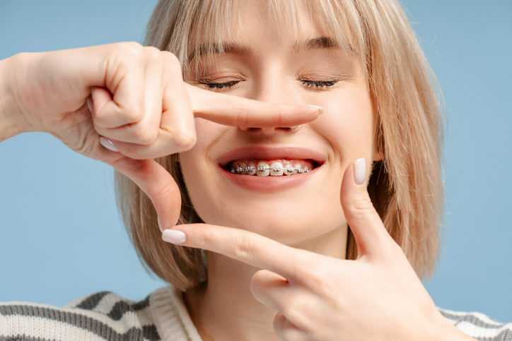 Cheerful woman with glasses smiling while framing her face with her hands