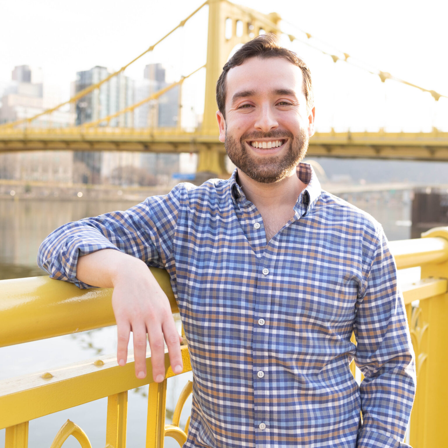Dr. Crell with his arm leaning on a rail in front of a yellow bridge.