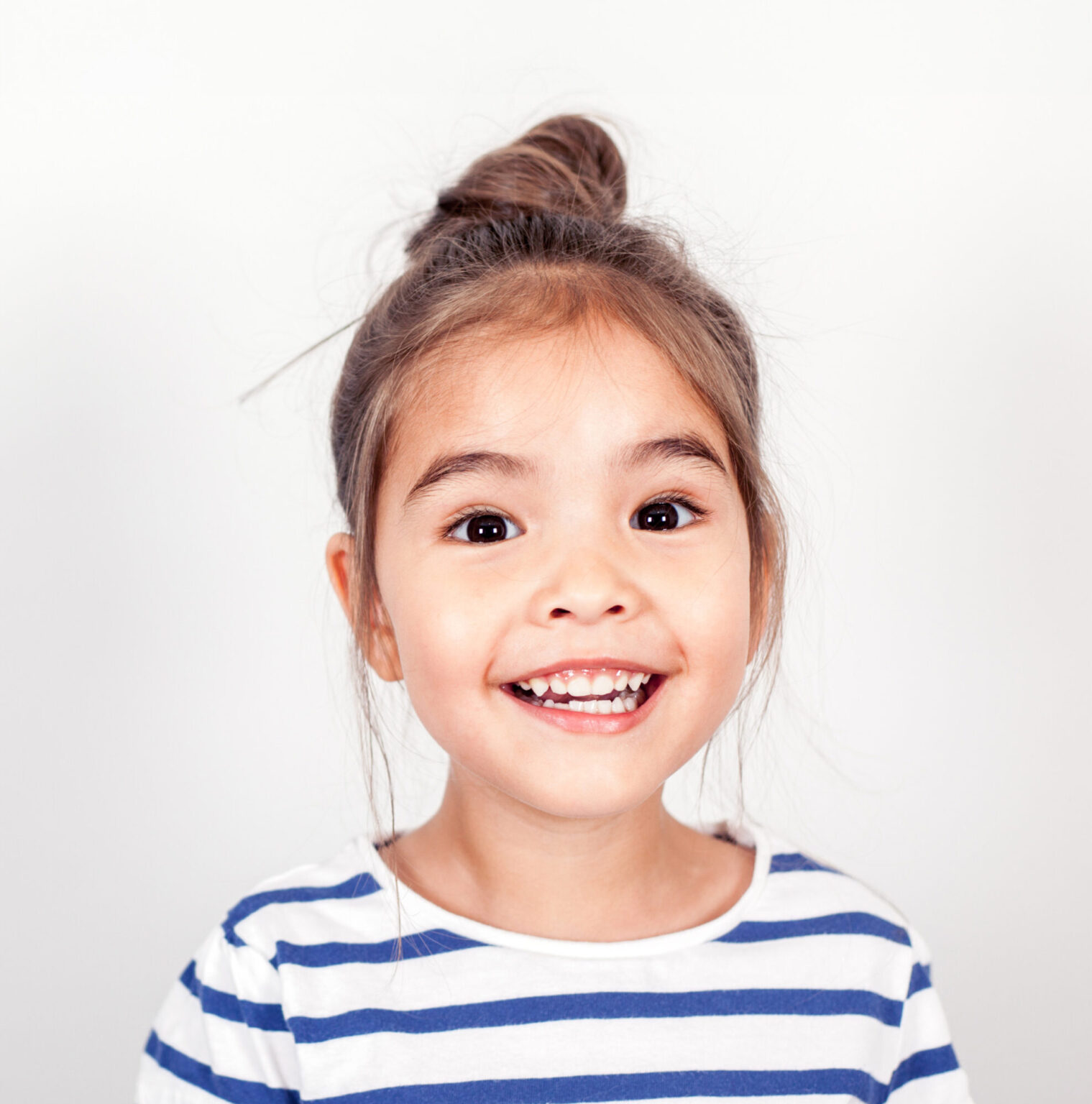 Small child in a blue and white striped shirt with a vibrant aligned smile